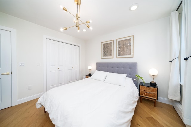 bedroom featuring a chandelier, light wood-style floors, and baseboards