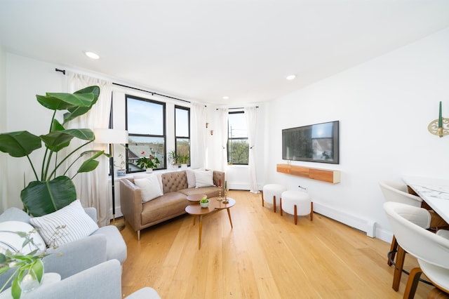 living room featuring light wood-style floors, recessed lighting, a baseboard heating unit, and baseboards