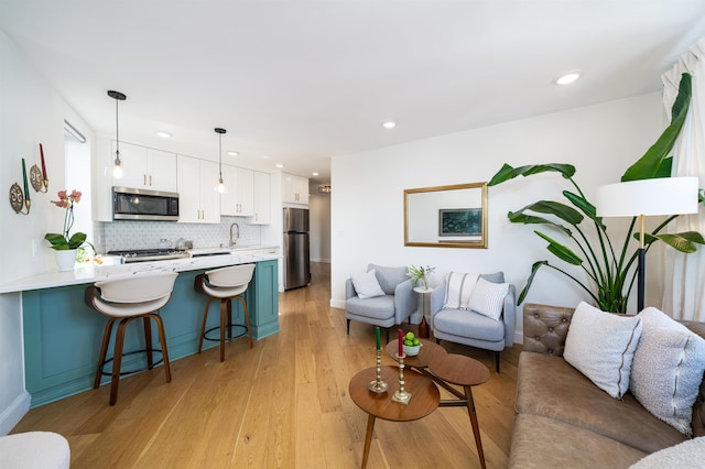 living area with baseboards, recessed lighting, and light wood finished floors