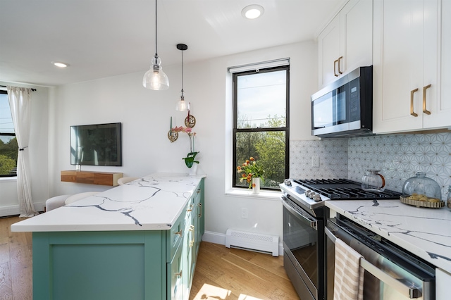 kitchen with stainless steel appliances, green cabinets, a healthy amount of sunlight, a peninsula, and baseboard heating