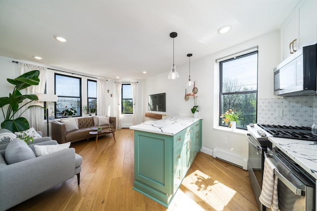 kitchen featuring light wood finished floors, stainless steel appliances, green cabinets, a peninsula, and a baseboard radiator
