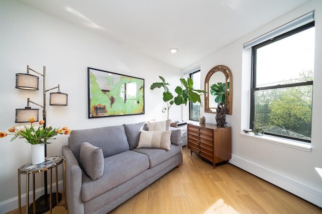 living room featuring recessed lighting, a baseboard radiator, vaulted ceiling, baseboards, and light wood-type flooring