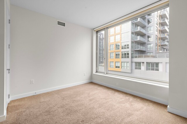 empty room with visible vents, carpet floors, and baseboards