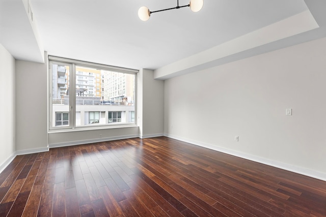 spare room with visible vents, baseboards, and dark wood-style flooring