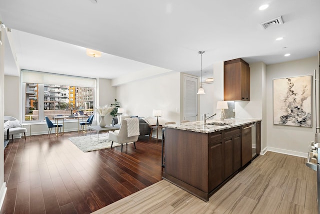 kitchen with visible vents, a sink, light wood-style floors, stainless steel dishwasher, and open floor plan