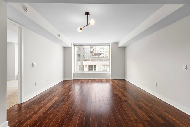 unfurnished living room featuring visible vents, baseboards, and wood finished floors