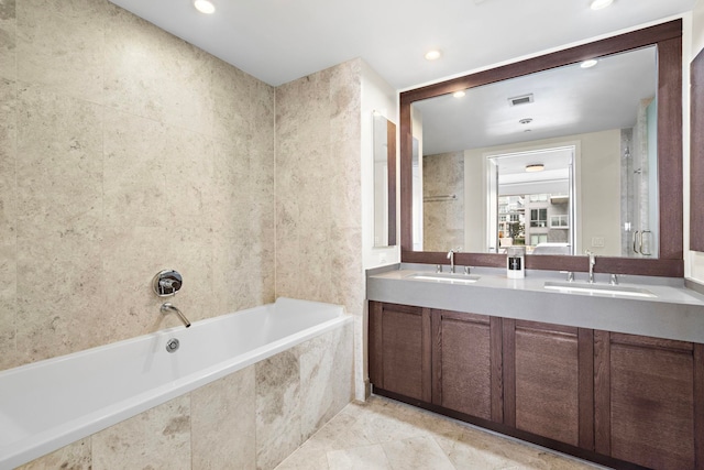 bathroom with a sink, recessed lighting, double vanity, and tiled bath