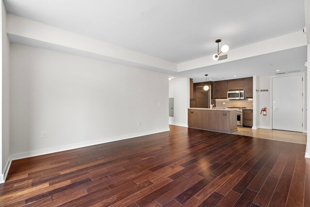 unfurnished living room featuring visible vents, baseboards, and wood finished floors