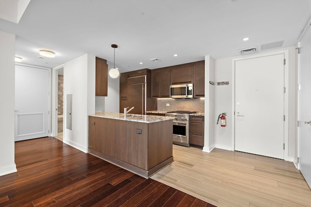 kitchen with visible vents, light wood-style floors, high end appliances, and a peninsula