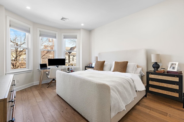 bedroom featuring visible vents, multiple windows, light wood-type flooring, and baseboards