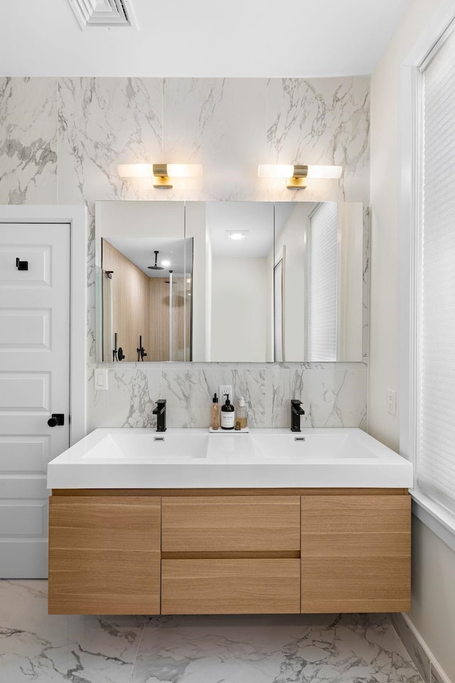 full bath with double vanity, visible vents, marble finish floor, and a sink