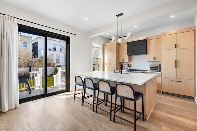 kitchen with backsplash, a breakfast bar, light wood-style flooring, and light brown cabinets