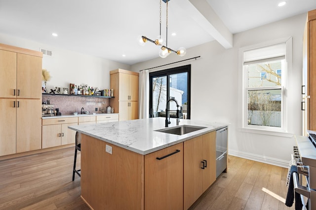 kitchen with an island with sink, visible vents, light brown cabinetry, and a sink