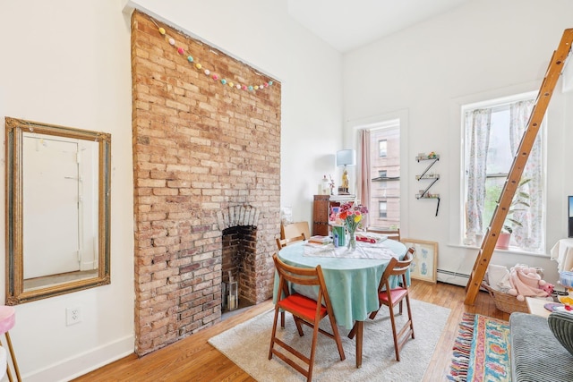 300 Barrow St, Jersey City, NJ 07302 - dining room featuring baseboards, light wood-style floors, and a brick fireplace