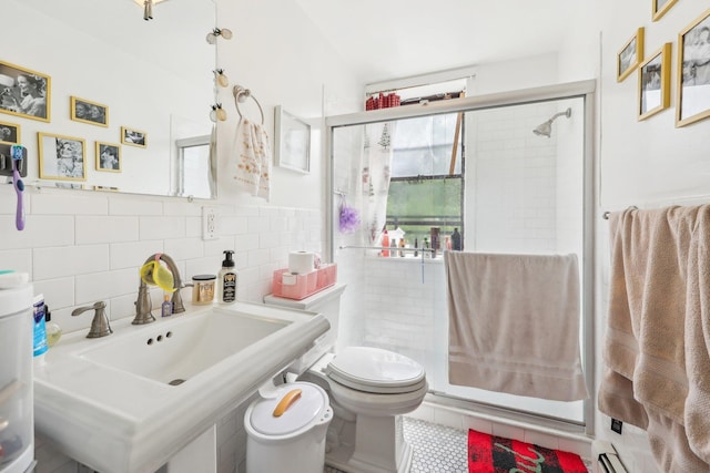 300 Barrow St, Jersey City, NJ 07302 - bathroom with tile walls, toilet, a sink, a shower stall, and tile patterned flooring