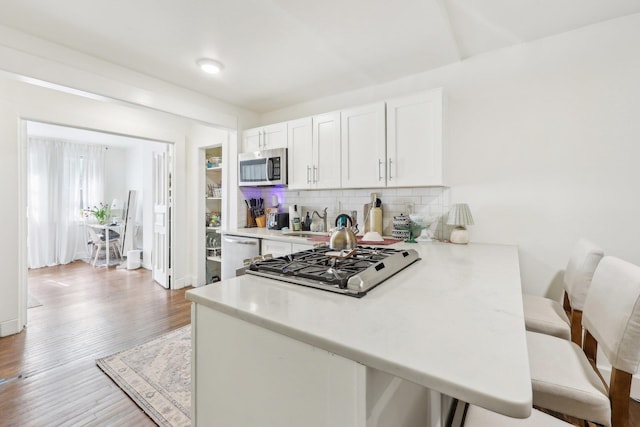 300 Barrow St, Jersey City, NJ 07302 - kitchen featuring stainless steel appliances, decorative backsplash, light wood-style floors, light countertops, and white cabinets