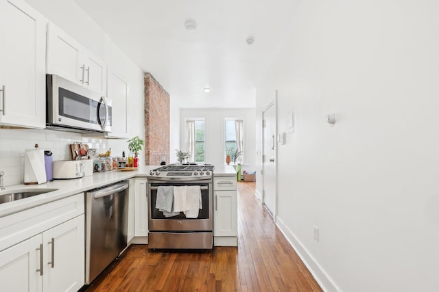 300 Barrow St, Jersey City, NJ 07302 - kitchen with dark wood-style flooring, a peninsula, decorative backsplash, stainless steel appliances, and white cabinets