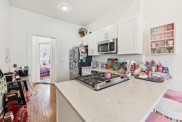 300 Barrow St, Jersey City, NJ 07302 - kitchen with light wood-style flooring, white cabinetry, a peninsula, decorative backsplash, and stainless steel appliances