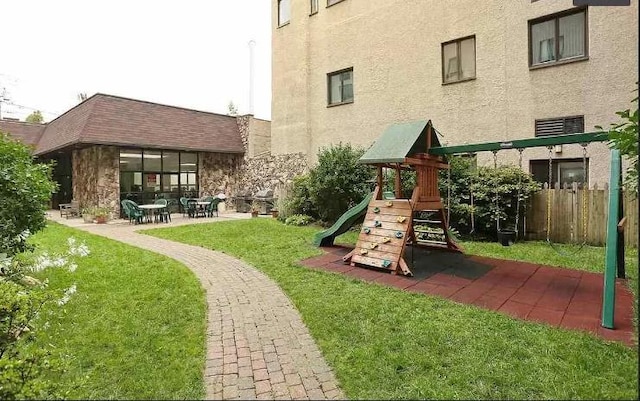 view of play area featuring a patio area, a lawn, and fence