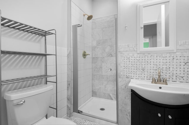 full bath with a shower stall, a wainscoted wall, toilet, vanity, and tile walls