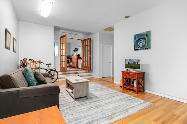 living area with french doors, baseboards, and wood finished floors