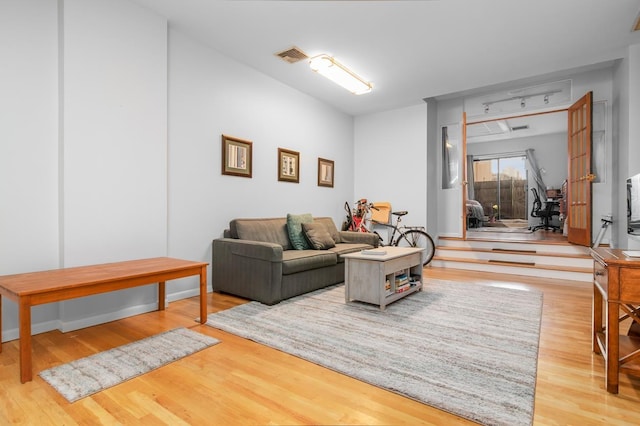 living room with wood finished floors, visible vents, and baseboards