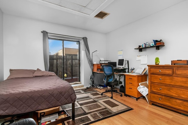 bedroom featuring access to exterior, attic access, wood finished floors, and visible vents