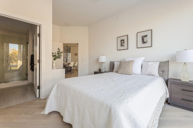 bedroom with light wood-style flooring and connected bathroom