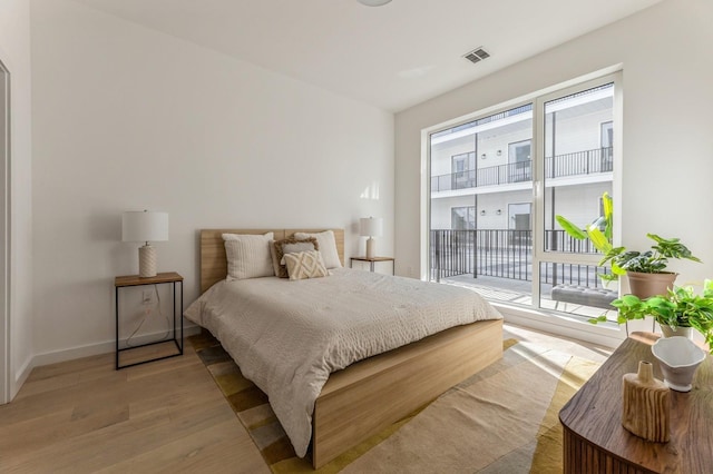 bedroom with visible vents, light wood-style flooring, baseboards, and access to outside