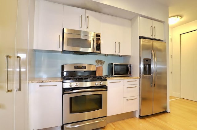 4 Beacon Way Unit 1110, Jersey City, NJ 07304 - kitchen featuring appliances with stainless steel finishes, light wood-style floors, white cabinets, and light stone counters