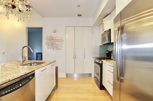 4 Beacon Way Unit 1110, Jersey City, NJ 07304 - kitchen featuring appliances with stainless steel finishes, a sink, light wood-type flooring, white cabinetry, and light stone counters