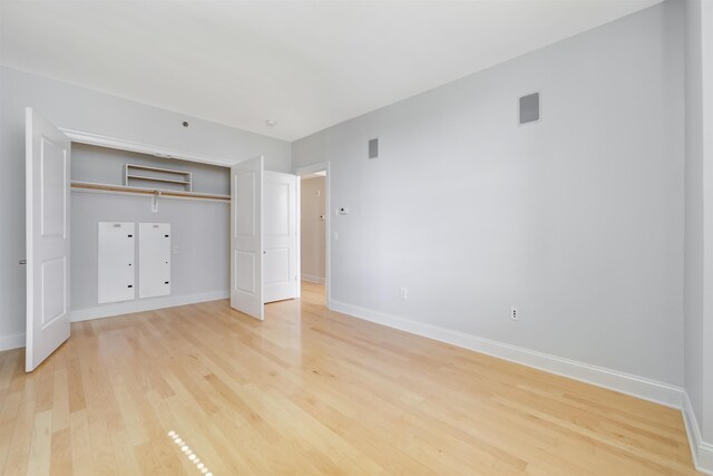 unfurnished bedroom featuring light wood-style flooring, visible vents, baseboards, and a closet