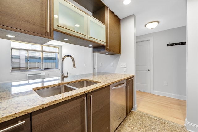 kitchen featuring a sink, light stone counters, glass insert cabinets, baseboards, and dishwasher