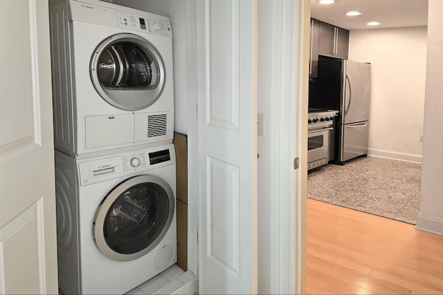 laundry area with light wood finished floors, baseboards, stacked washer and dryer, laundry area, and recessed lighting