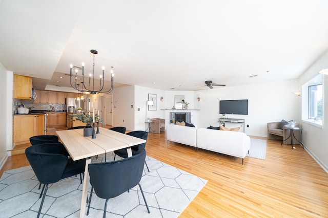 721 Madison St Unit 4N, Hoboken, NJ 07030 - dining room featuring light wood-style floors, a chandelier, a ceiling fan, a glass covered fireplace, and recessed lighting