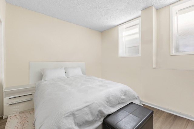 bedroom featuring hardwood / wood-style flooring, a textured ceiling, and multiple windows