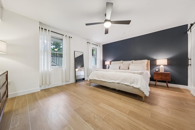 243 3rd St Unit 1, Jersey City, NJ 07302 - bedroom featuring a barn door, light wood finished floors, and a ceiling fan