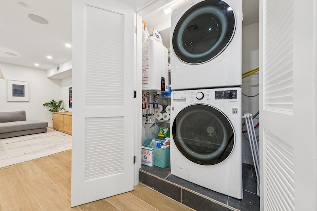243 3rd St Unit 1, Jersey City, NJ 07302 - washroom with stacked washing machine and dryer, tankless water heater, wood finished floors, and recessed lighting