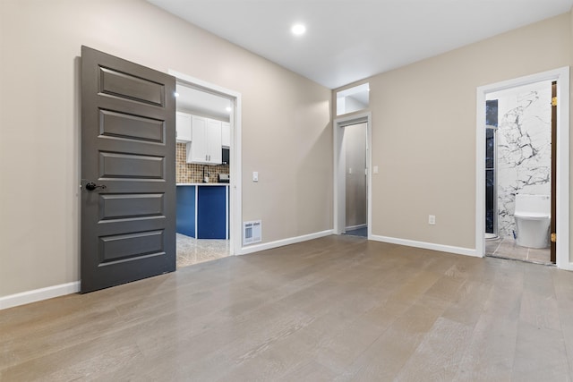 99 W 50th St, Bayonne, NJ 07002 - unfurnished bedroom with light wood-type flooring, recessed lighting, baseboards, and ensuite bathroom