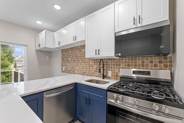 99 W 50th St, Bayonne, NJ 07002 - kitchen with stainless steel appliances, a sink, white cabinetry, blue cabinetry, and backsplash