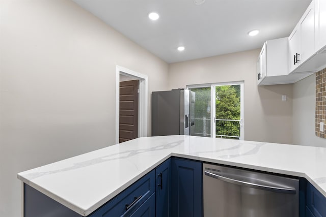 99 W 50th St, Bayonne, NJ 07002 - kitchen with appliances with stainless steel finishes, white cabinetry, blue cabinetry, recessed lighting, and light stone counters