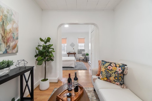 living area featuring cooling unit, crown molding, and light hardwood / wood-style floors