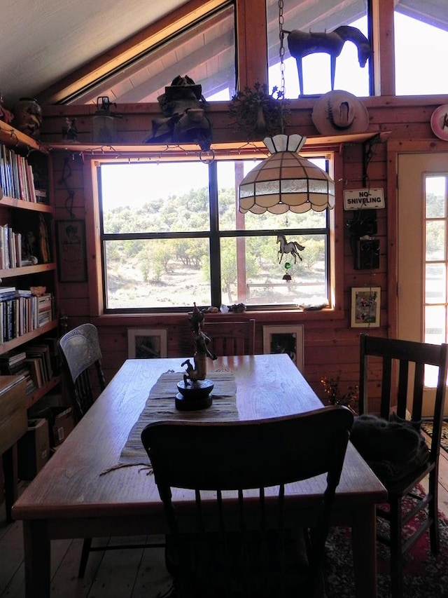 dining room with wood walls and lofted ceiling with beams