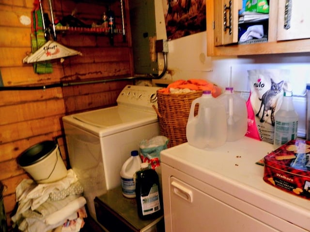 clothes washing area featuring wooden walls and independent washer and dryer