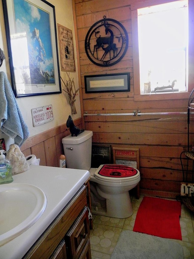 bathroom featuring vanity, toilet, and wood walls