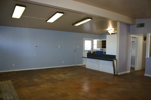 kitchen featuring kitchen peninsula, vaulted ceiling, and dark parquet flooring