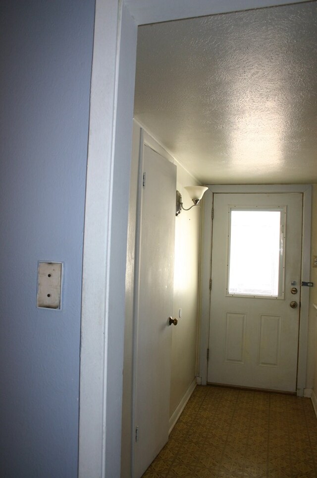 doorway to outside with a textured ceiling