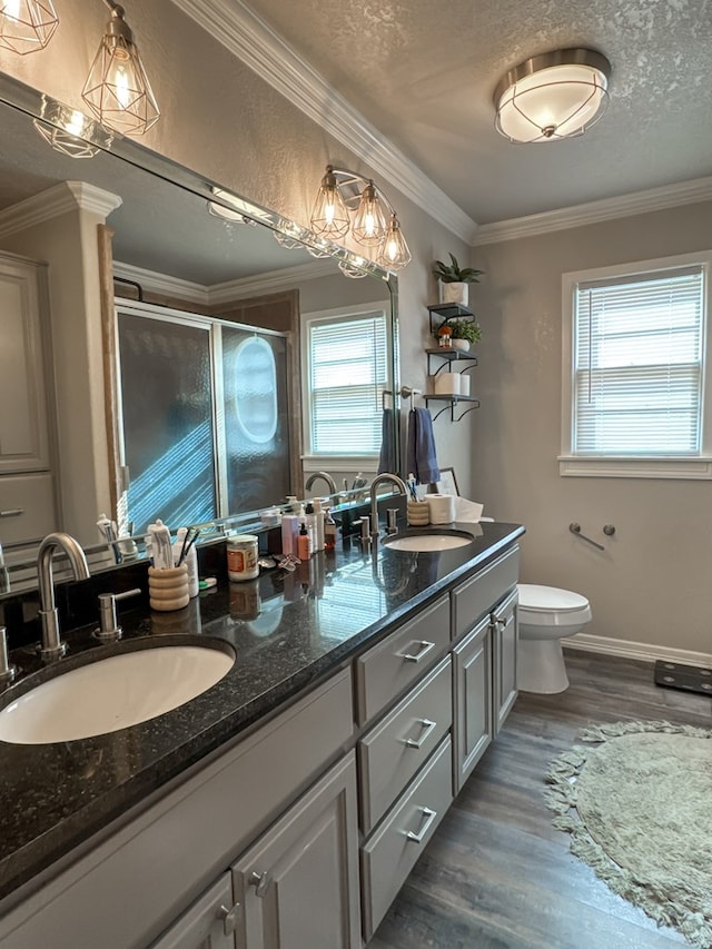 full bathroom with double vanity, wood finished floors, a stall shower, and a sink