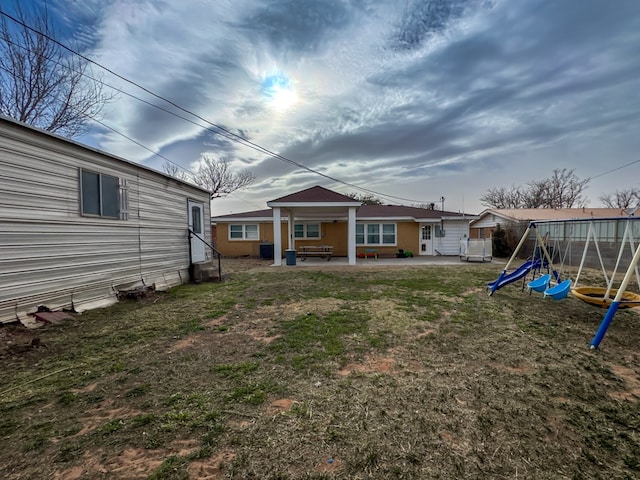 rear view of property with entry steps, a playground, and a patio