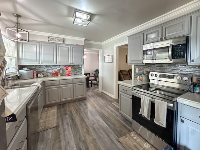 kitchen featuring appliances with stainless steel finishes, ornamental molding, wood finished floors, light countertops, and gray cabinets